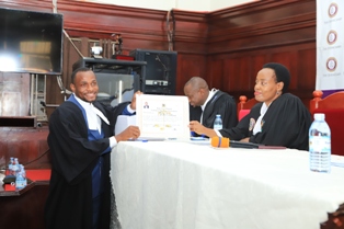 New Advocates Encouraged to Embrace Technology Professionalism and Ethics - HW Bareebe, Registrar High Court (R) handing over a certificate to one of the enrolled advocates