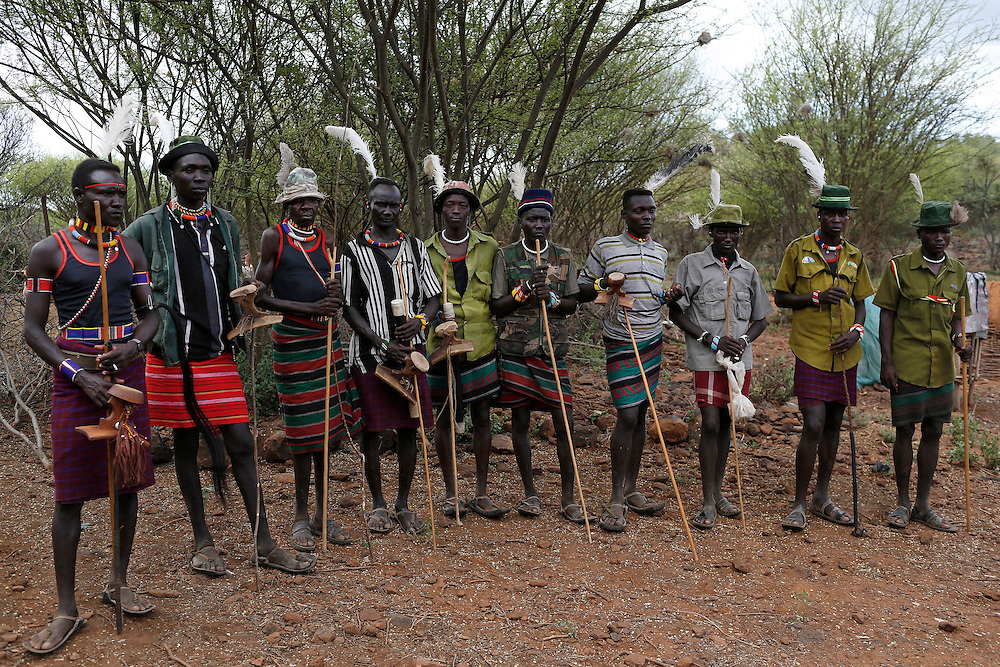 Pokot men stand near the home of a girl to be taken as wife for a member of their group