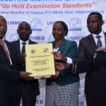 State Minister for Higher Education John Chrysestom Muyingo (left) receives the 2023 final semester UNMEB examination results from chairperson
