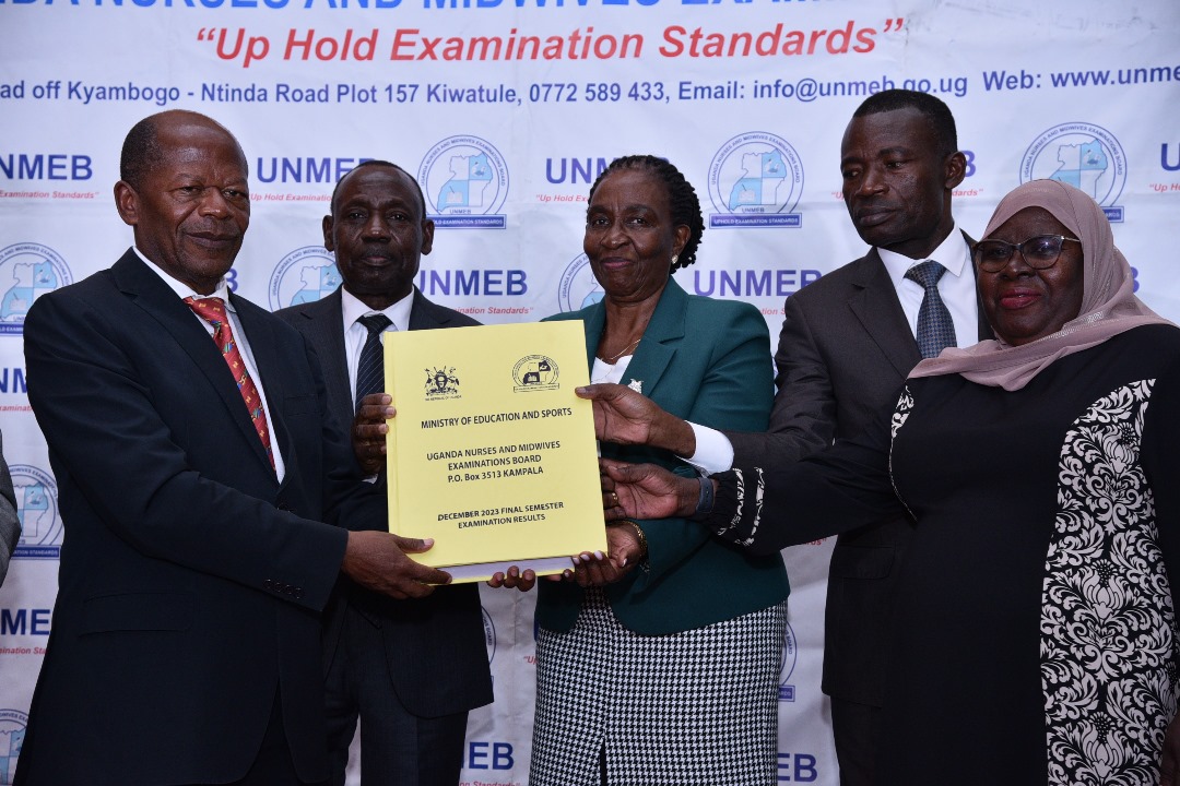 State Minister for Higher Education John Chrysestom Muyingo (left) receives the 2023 final semester UNMEB examination results from chairperson