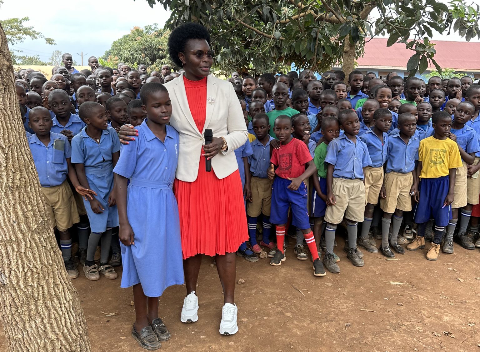 Hon. Dr. Lillian Aber Minister of State for Relief, Disaster Preparedness and Refugees sharing a light moment with pupils of Kiteezi C.O.U which hosted the IDP Camp